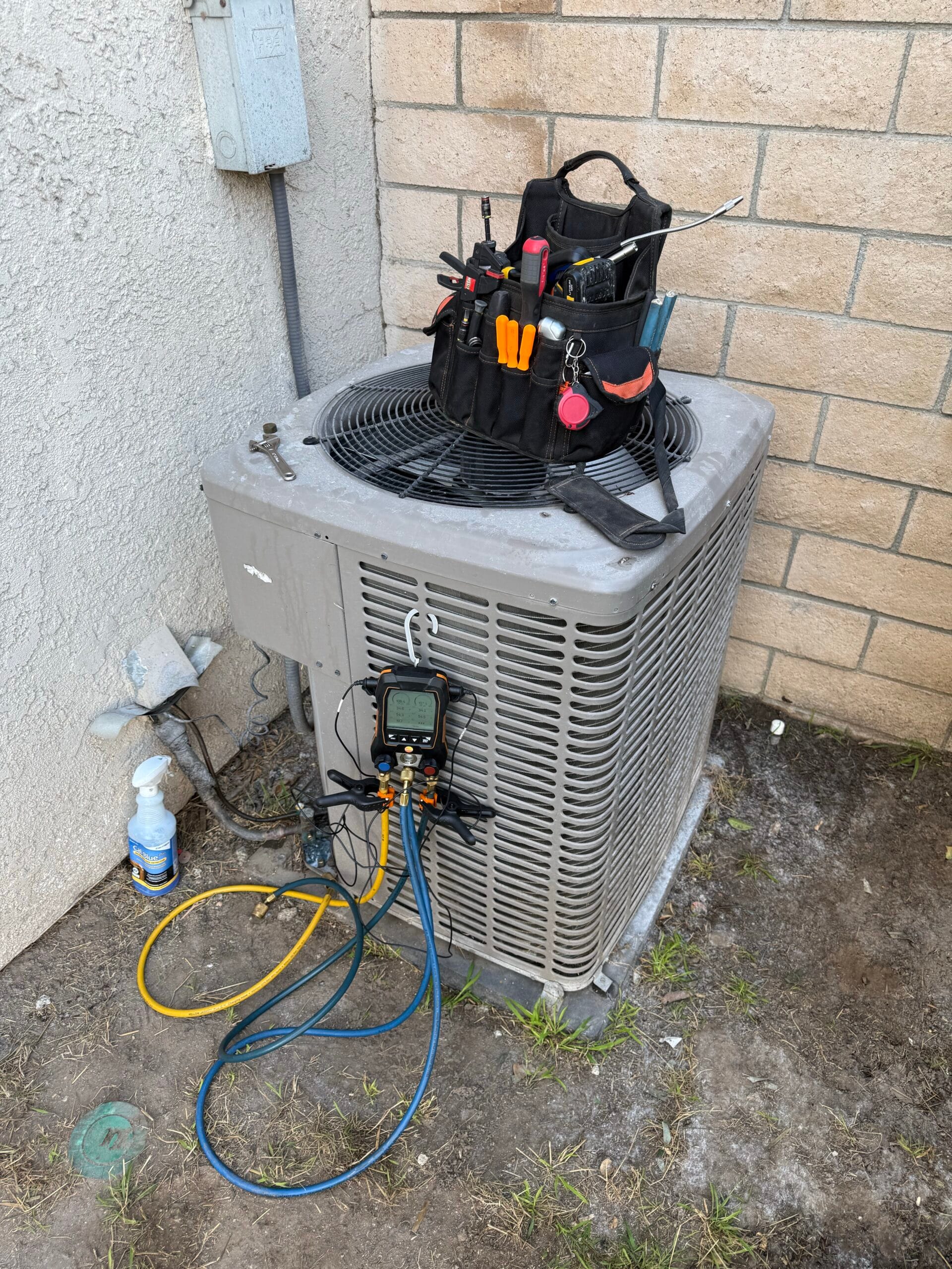 Smartchoice technician checking an AC condenser with refrigerant gauges connected
